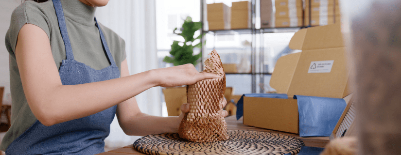 A shop owner packaging something in recycled paper wrapping.