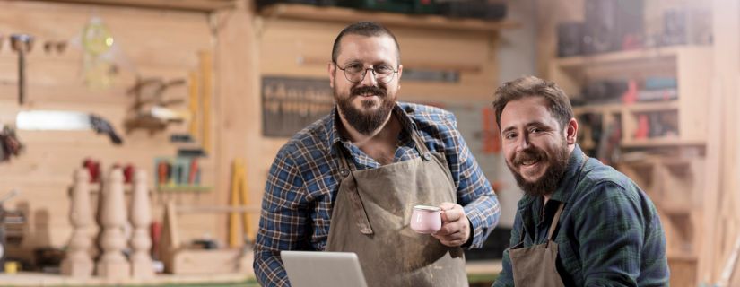 two men who are small business owners with their computer in their workshop.