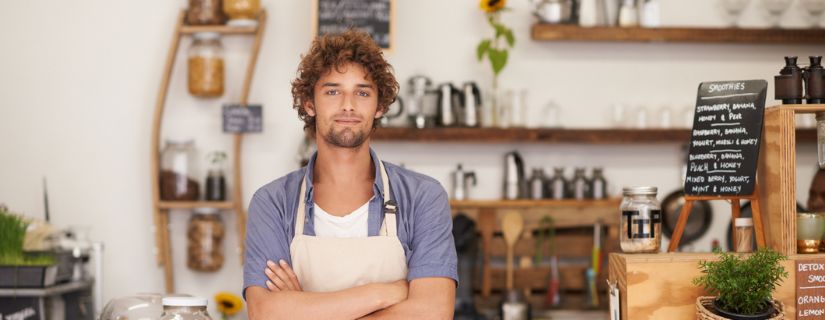 A man wearing an apron in his restaurant looking happy.