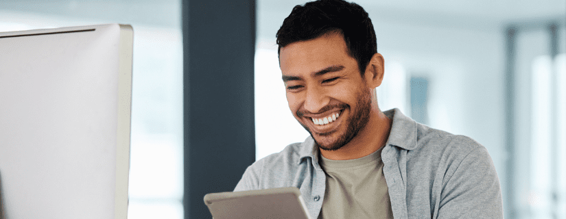 A happy young, male, business owner smiling at his web notifications he set up for his company.